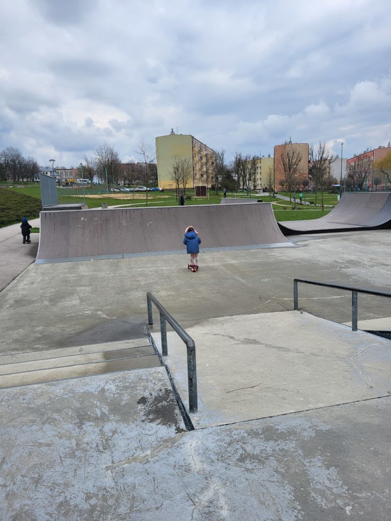 Skatepark: Busko Zdrój - widok ze schodów. Dziewczynka na hulajnodze.