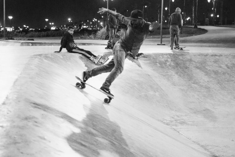 Grupa ludzi surfuje nocą w skateparku. Surfskate Curfboard SE.